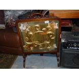 An Fire screen with ornate wooden frame and embroidered front.