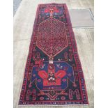 A large Iranian runner in red and black with blue border with geometric design,