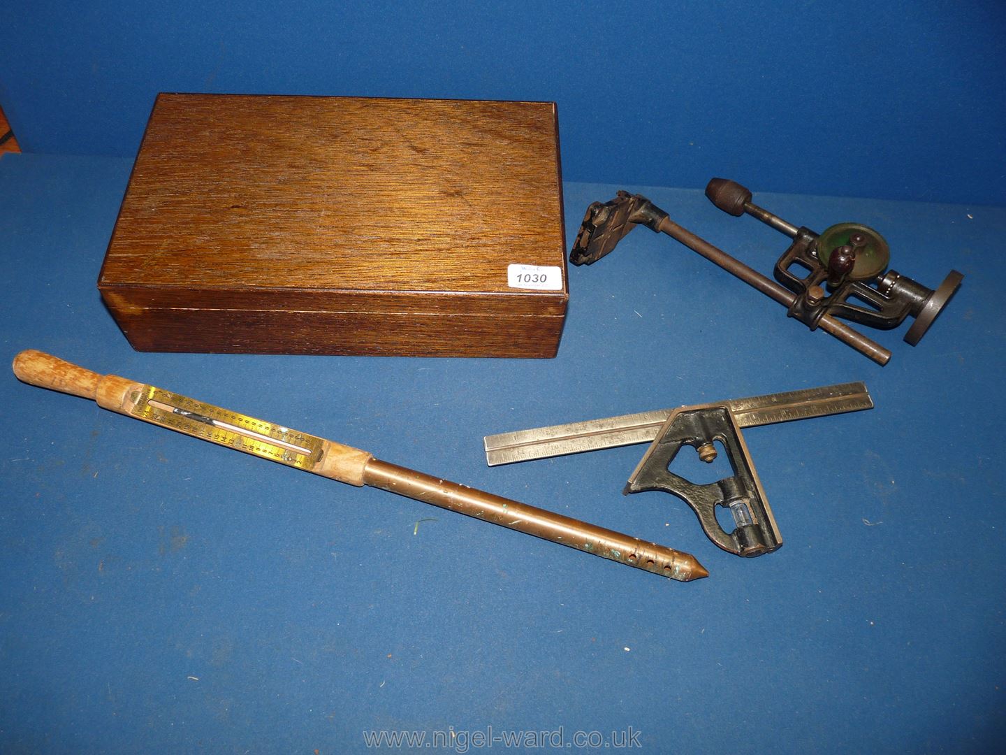 A vintage ground thermometer, wrought iron tower drill and set square in wooden box.