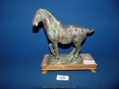 A cast metal bronzed effect Tang Dynasty style horse on a wooden plinth, 9" tall.