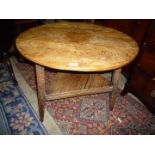 A mellow Oak and Elm peg-joyned Cricket Table having triangular lower shelf uniting the three legs.