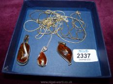 Five silver chains with three amber pendants with silver surround.