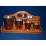 A graduated set of copper ale measures marked HMS to base with a wooden stand fitted with copper