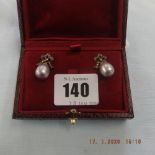 A pair of grey pearl drop earrings set with diamond bow tops