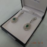 A pair of 18ct white gold pear drop emerald and diamond cluster earrings,