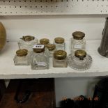 Nine glass inkwells with brass lids