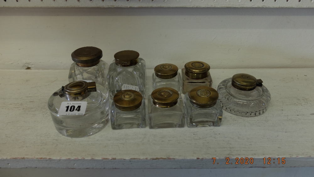 Nine glass inkwells with brass lids