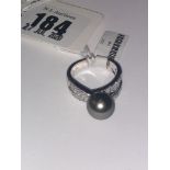An 18ct white gold black pearl ring with diamond clusters,  size O