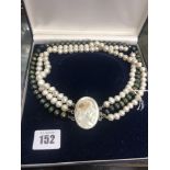 A three strand pearl necklace with a cameo clasp