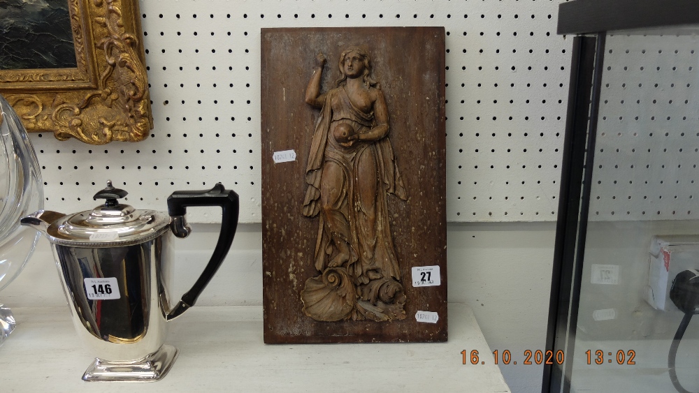 A carved wooden plaque of a lady holding ball,