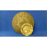 A decorative wall plaque and a brass dish