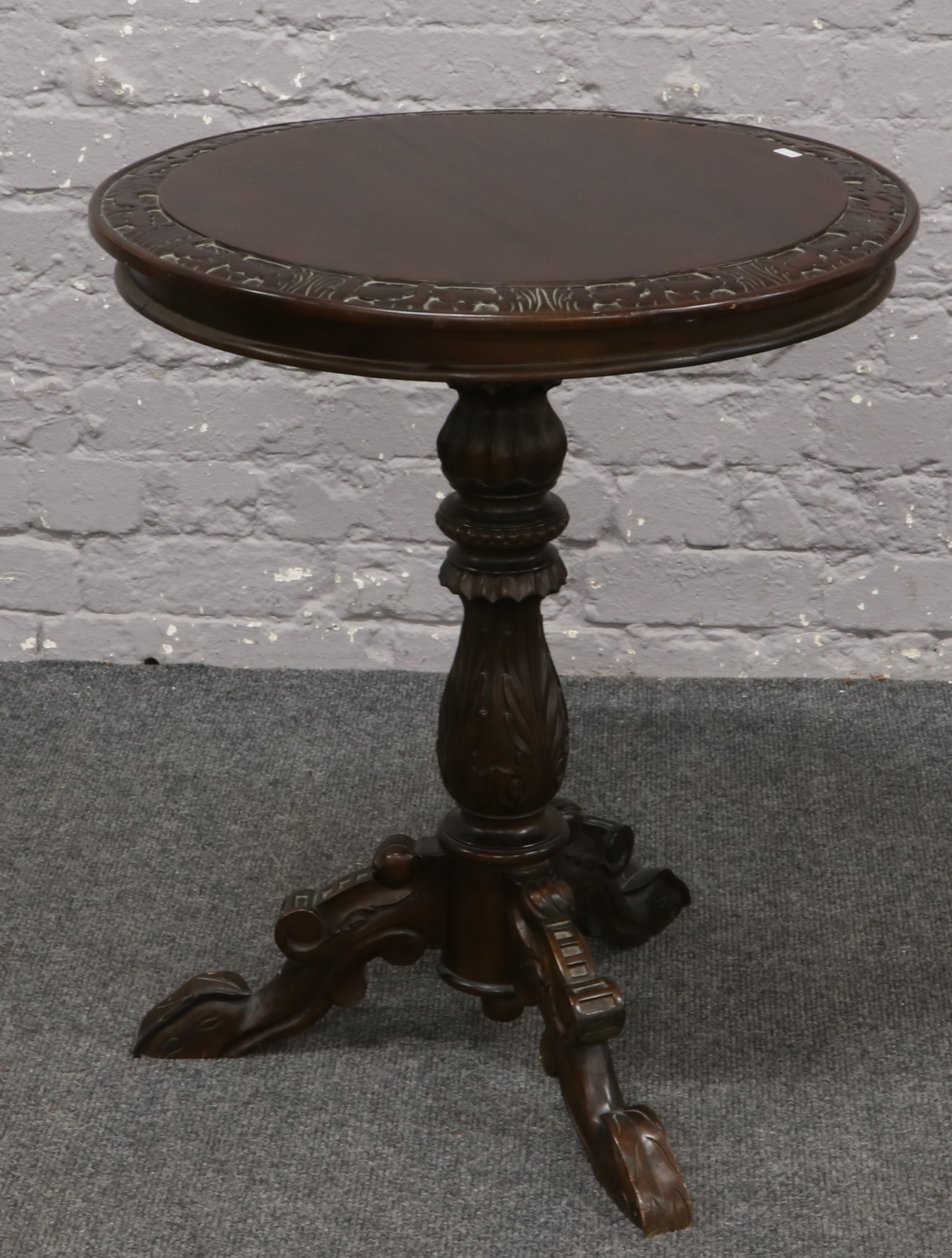 A carved mahogany occasional table raised on extensively carved supports.