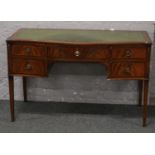 A mahogany serpentine shaped writing desk with inset green leather top raised on tapering square