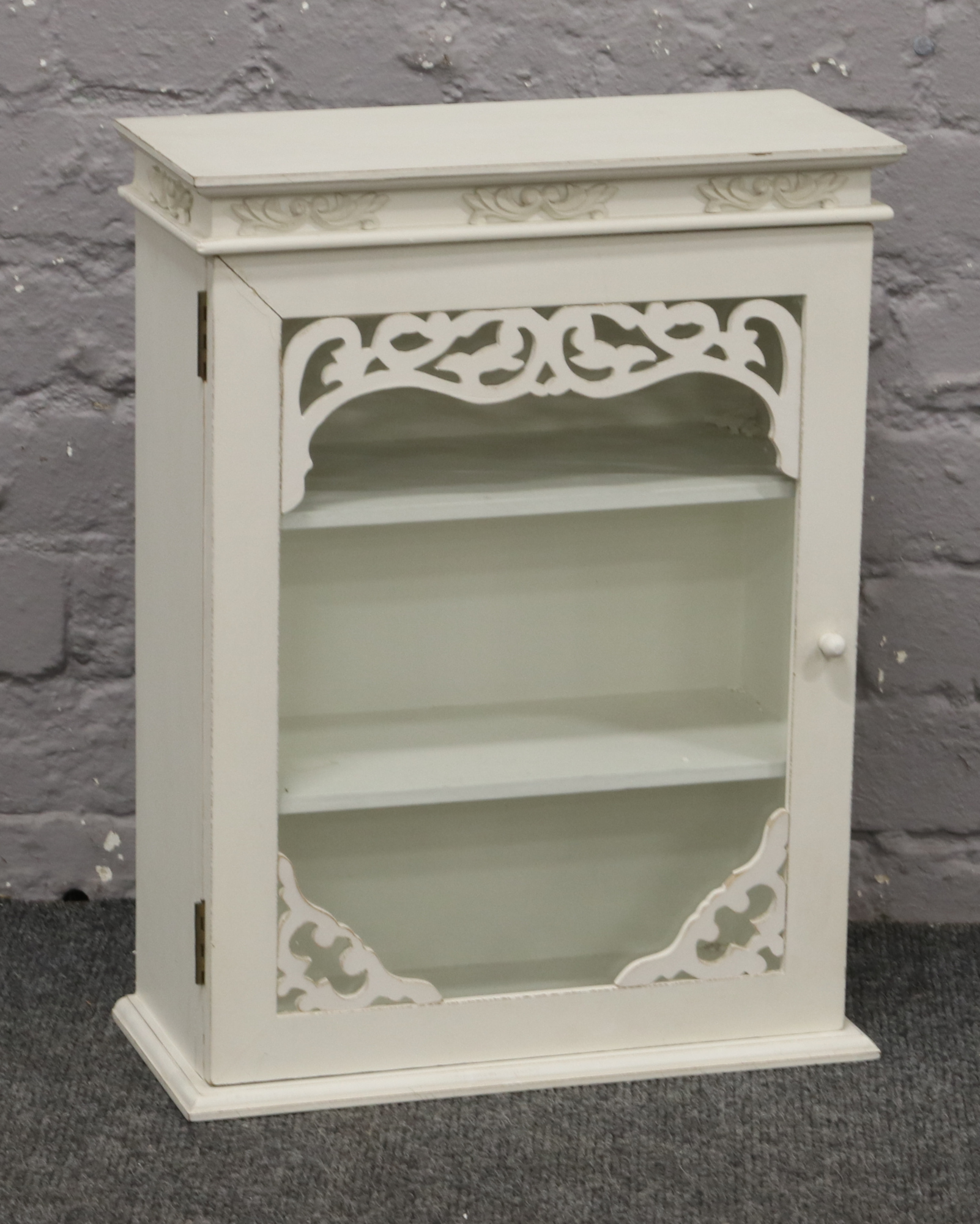 A white painted glass front three shelf bathroom cabinet.