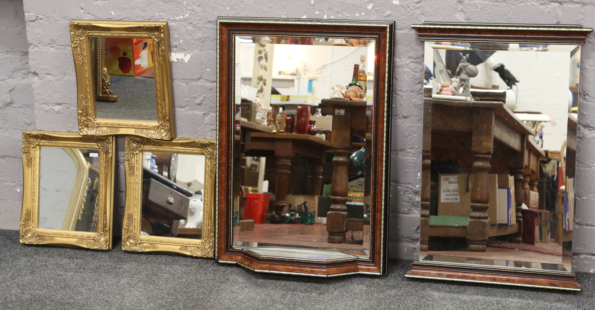 Two mahogany bevel edge wall mirrors, one with mirrored shelf, along with three gilt framed mirrors.