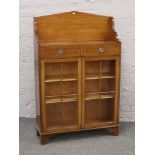 A George V mahogany two drawer display cabinet with triangular pediment.