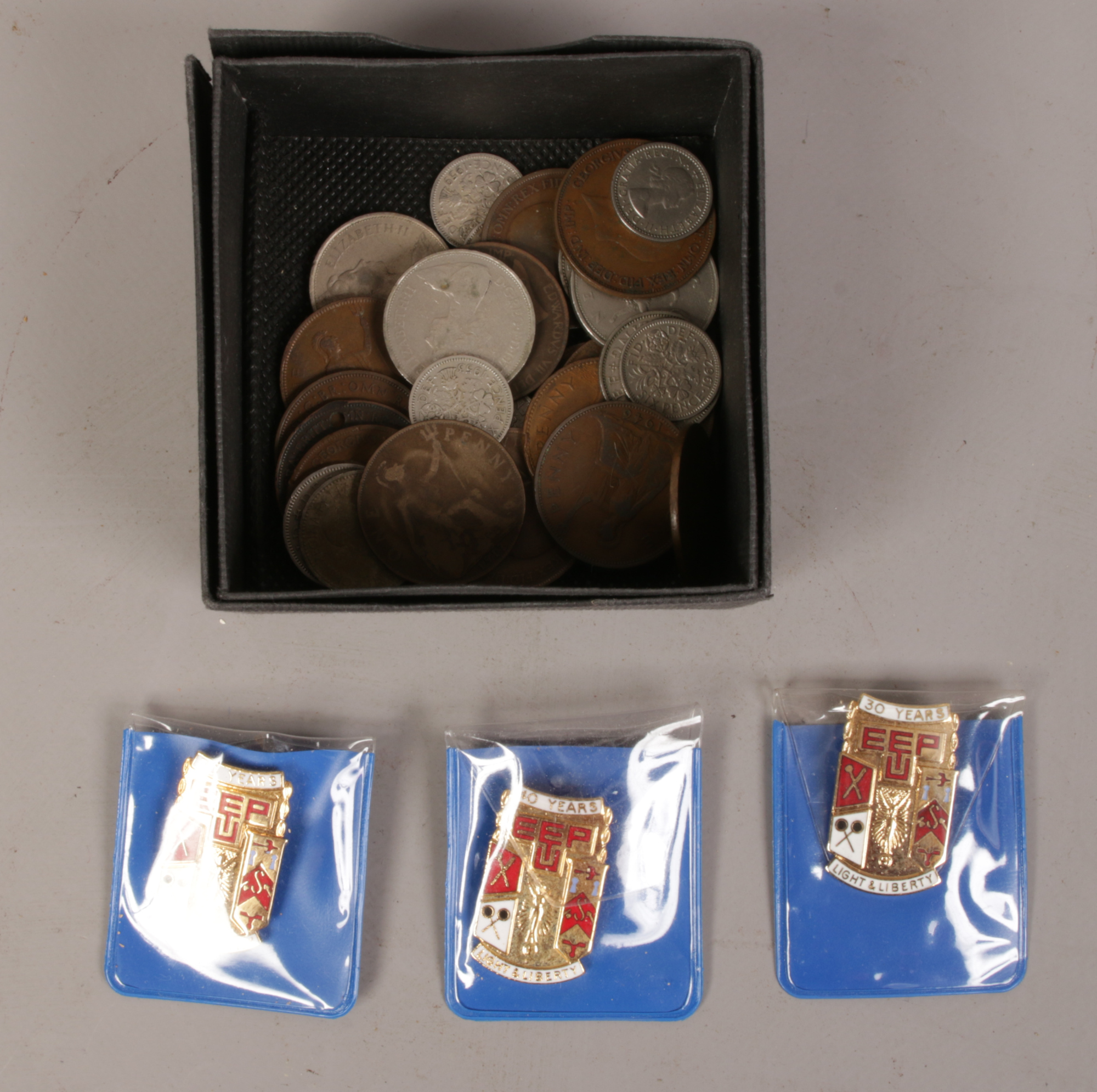 A small collection of British copper and silver coins, along with three EETPU Union badges.