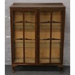 A carved oak display cabinet with two glass shelves.
