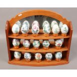 Sixteen Princeton gallery porcelain eggs, decorated with unicorns on mirrored back display stand.