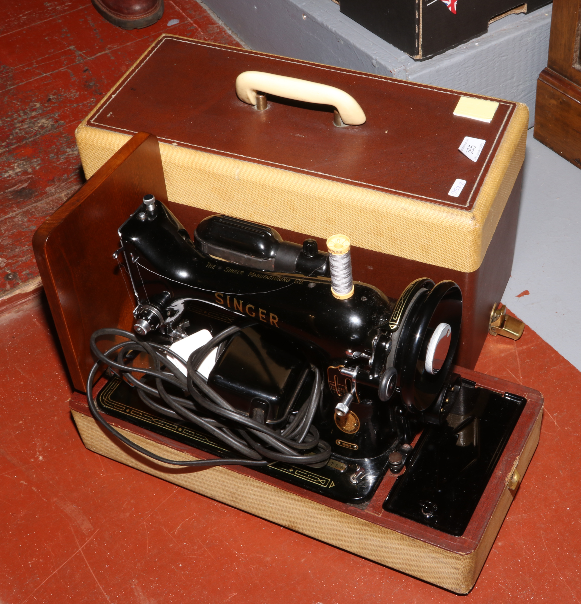 A cased Singer electric sewing machine.