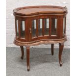A mahogany Kidney shaped drinks cabinet with serving tray raised on scroll supports.