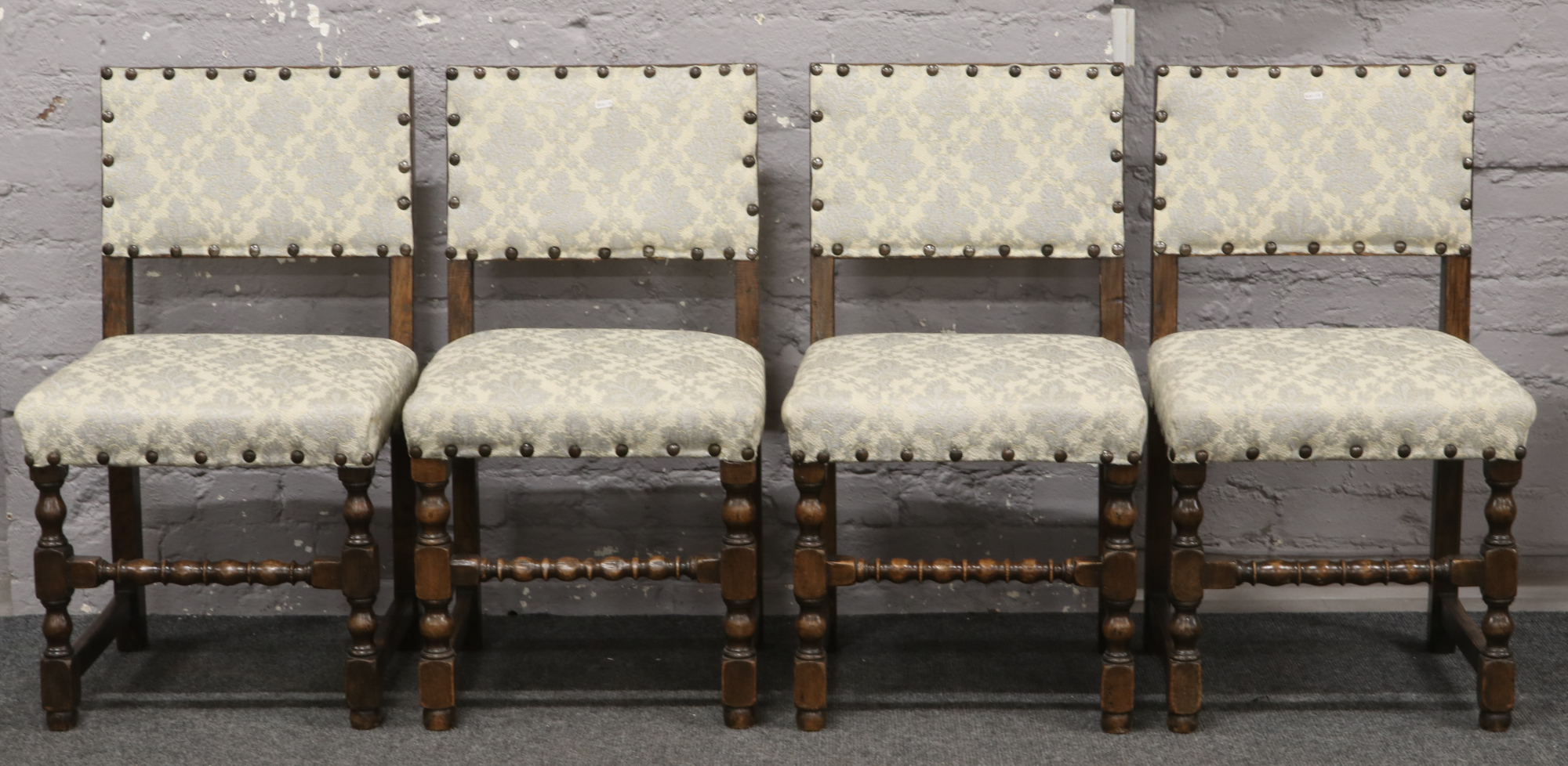 A set of four oak padded dining chairs with spindle cross stretchers.