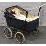 A vintage dolls pram with contents of dolls.