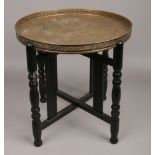 An Indian brass top table on wood folding base.