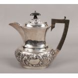 An Edwardian silver hot water jug. With hardwood handle and decorated with repousse scrolls. Assayed