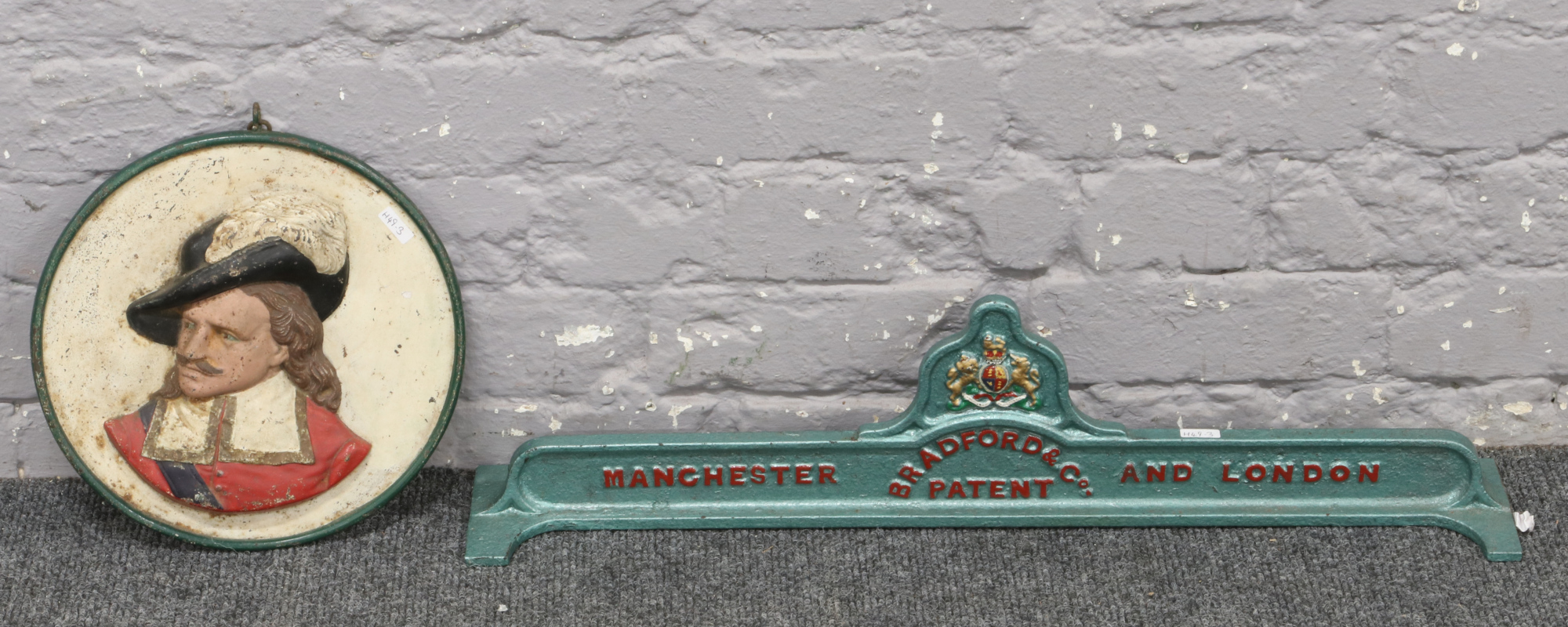 A painted cast iron mangle top, along with a cast iron wall plaque of a cavalier.