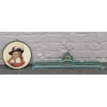 A painted cast iron mangle top, along with a cast iron wall plaque of a cavalier.