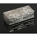 A white metal two compartment pill box. One side chased with corn and the other with roses.