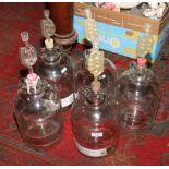 Five glass demijohns.