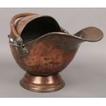 A copper coal scuttle with copper swing handle.