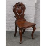 A Victorian carved mahogany hall chair raised on cabriole supports.