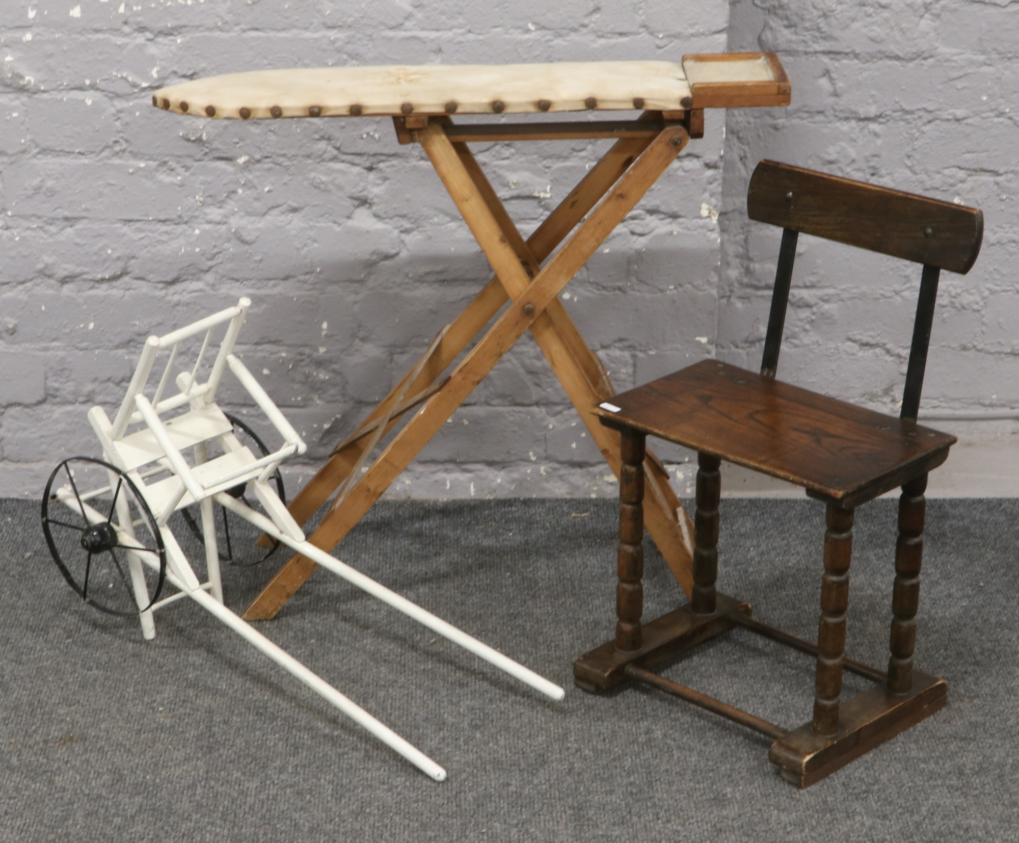 A child's ironing board, chair and pull along cart.