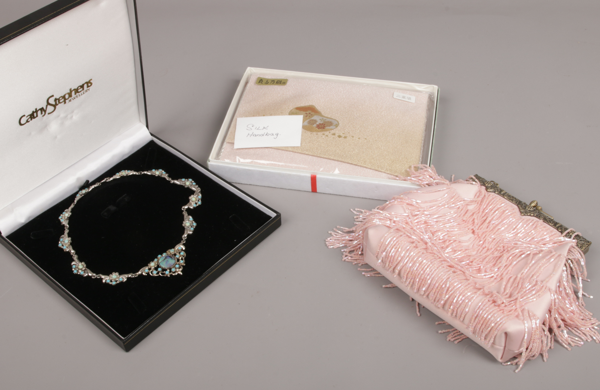 A cased ladies white metal necklace, along with two handbags, one Chinese silk the other with