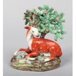 An early 19th century Staffordshire pearlware figure. Formed as a recumbent spotted deer leaning