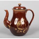 A Brameld brown glazed earthenware teapot and cover of baluster form and decorated in gilt with