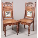 A pair of Victorian carved oak hall chairs. Each set with a printed tile to the backrest depicting