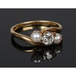 An antique 18 carat gold diamond and pearl crossover ring. With a central round cut diamond