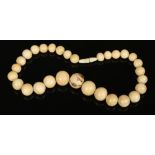 A Japanese Meiji period ivory bead necklace. With graduated beads, the central bead carved and