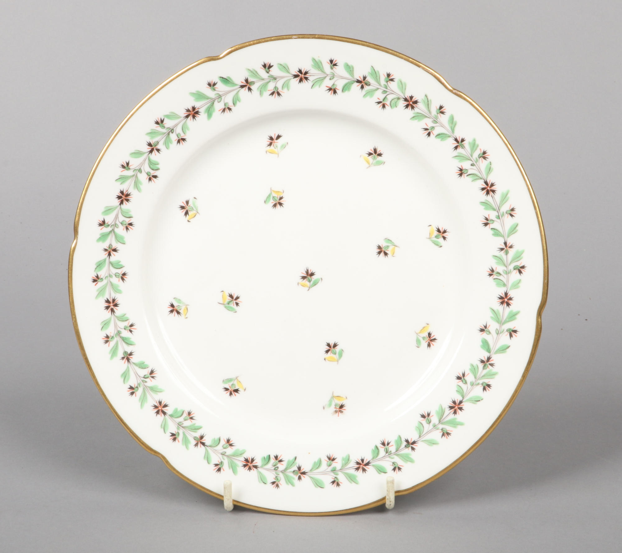 A Rockingham lobed dessert plate with gilt rim. Painted in coloured enamels with a trailing border