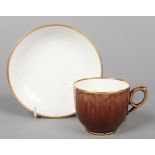 A Staffordshire brown-glazed porcelain coffee cup and saucer with gilt edging. Decorated by