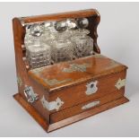 A George V oak three bottle tantalus with silver plated mounts. With mirrored back, fitted