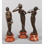 Three Art Nouveau style bronze figures of maidens raised on variegated red marble socle bases, 22cm.