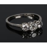 An antique platinum three stone diamond ring. Set with three graduated brilliant cut diamonds,