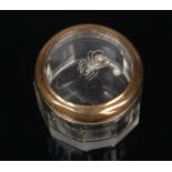 A faceted glass small dressing table pot. The cover with brass mount is decorated with an encased