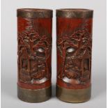 A pair of Chinese carved bamboo brush pots with metal banded rims. Each decorated in relief with a