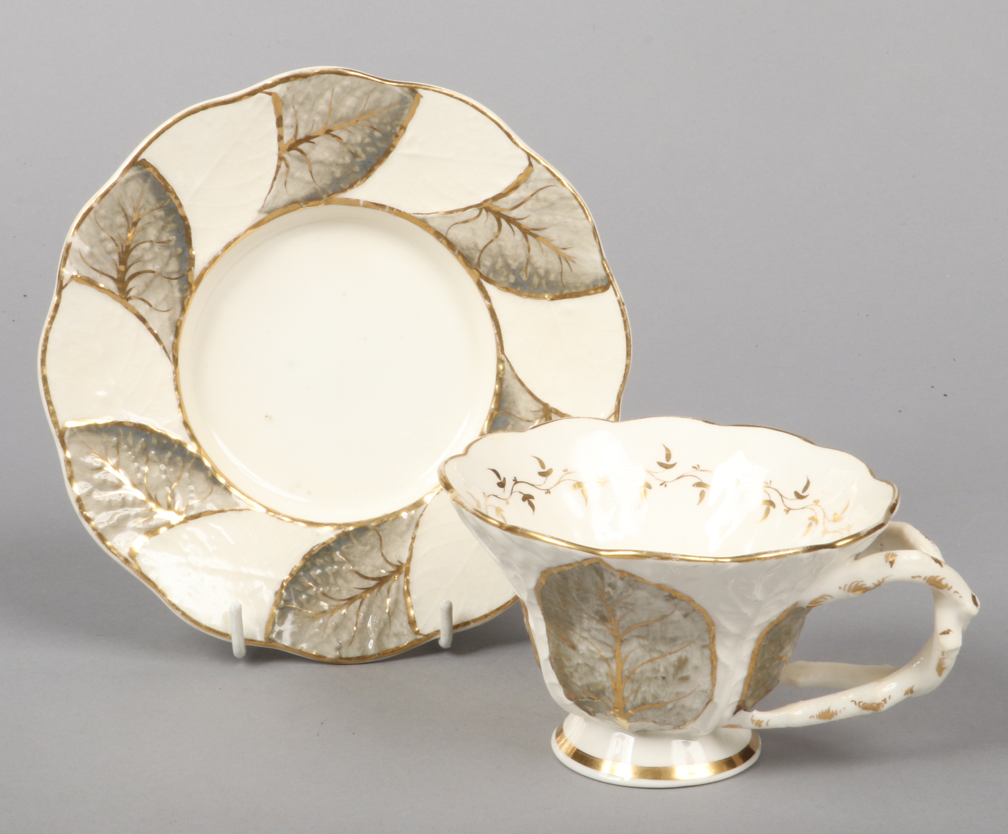 A Rockingham primrose leaf moulded breakfast cup and saucer with rustic crossed-twig handles.